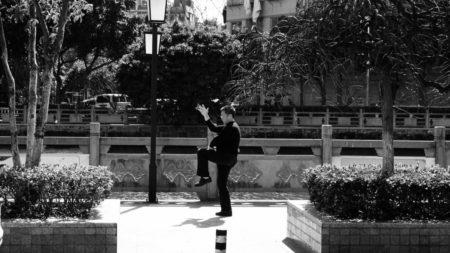 black and white photo of a man exercising tai chi in a city